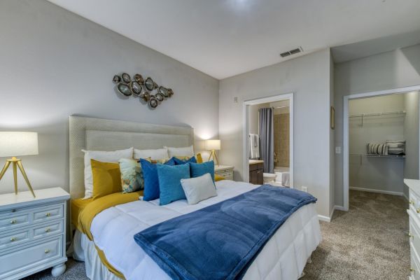 Integra Landing A cozy bedroom with a large bed, blue and yellow bedding, nightstands, and an open door to a bathroom.