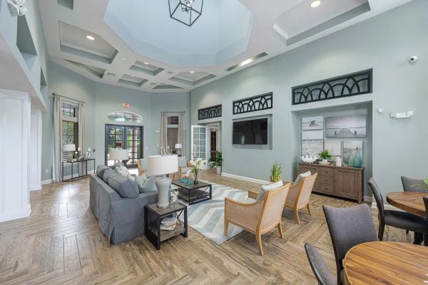 Integra Landing Modern living room with gray couches, wooden chairs, and large windows under a coffered ceiling.
