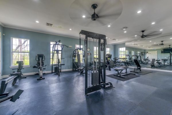 Integra Landing Spacious gym room with various exercise machines, weight equipment, and blue walls with large windows.