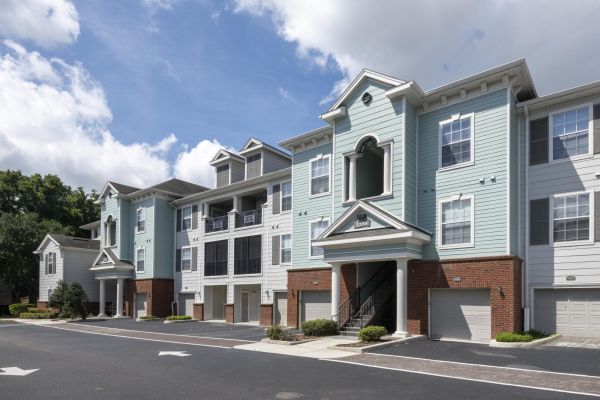 Integra Landing Modern light blue apartment building with garages, large windows, and a sunny, partly cloudy sky.
