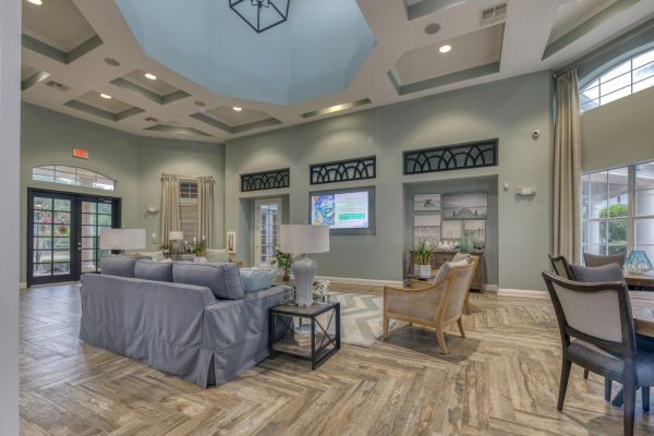Integra Landing Spacious, elegant lounge with sofas, chairs, TV, large windows, and patterned wooden floors under a high ceiling.